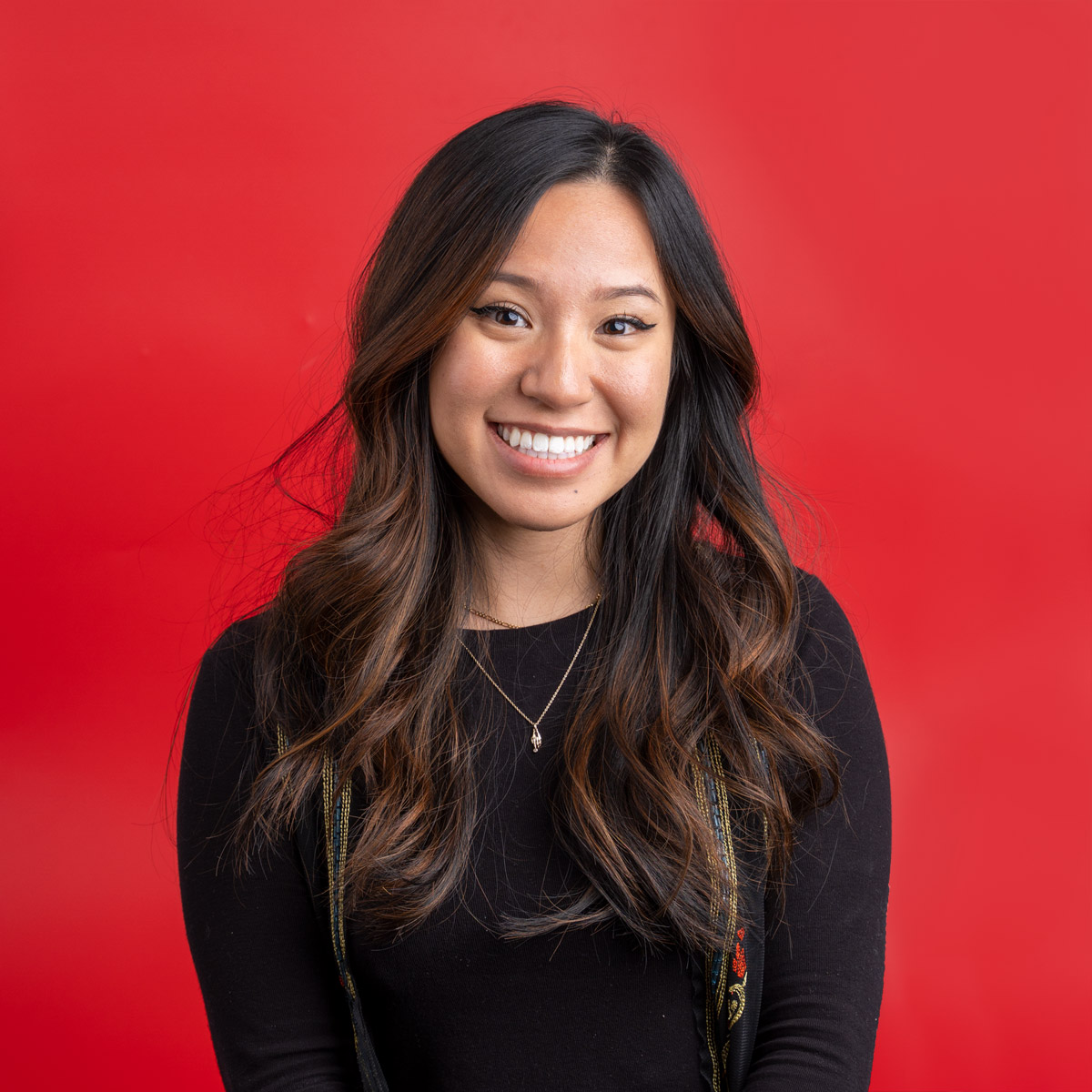 A woman smiling against a red backdrop.